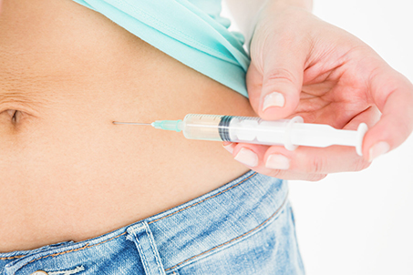 Closeup of person giving a self-injection in the abdomen